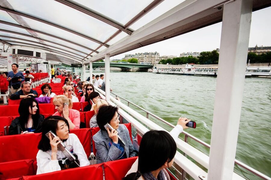 Paris: Audio-Guided Bus Tour & Seine River Cruise - Boarding the glass-sided trimaran near the Eiffel Tower